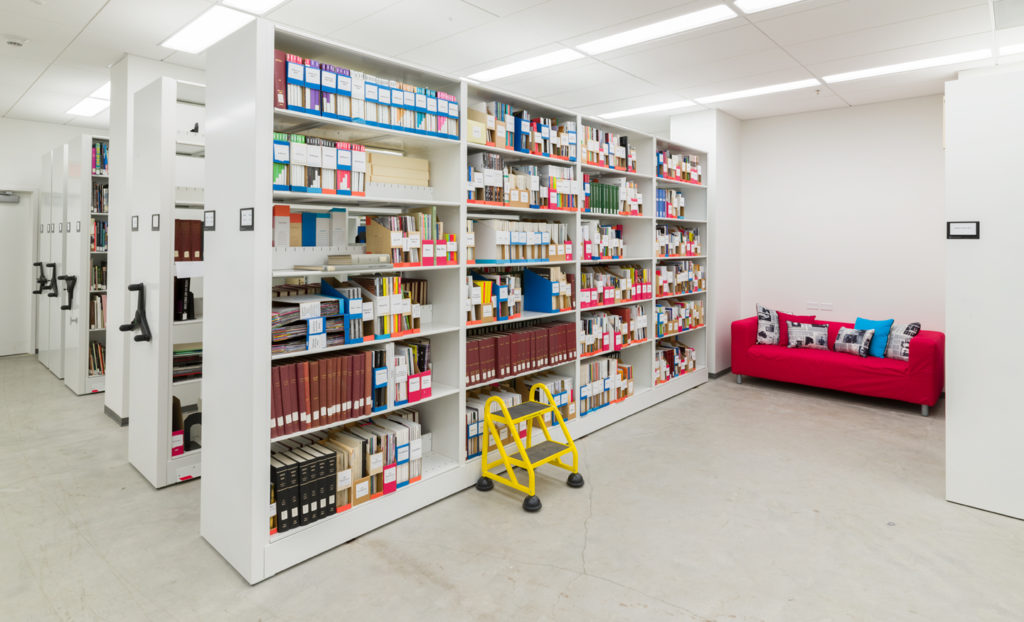 Bookshelves filled with files and flanked by a red couch