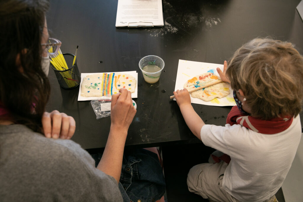 A child and an adult sit at a table making an art project together.