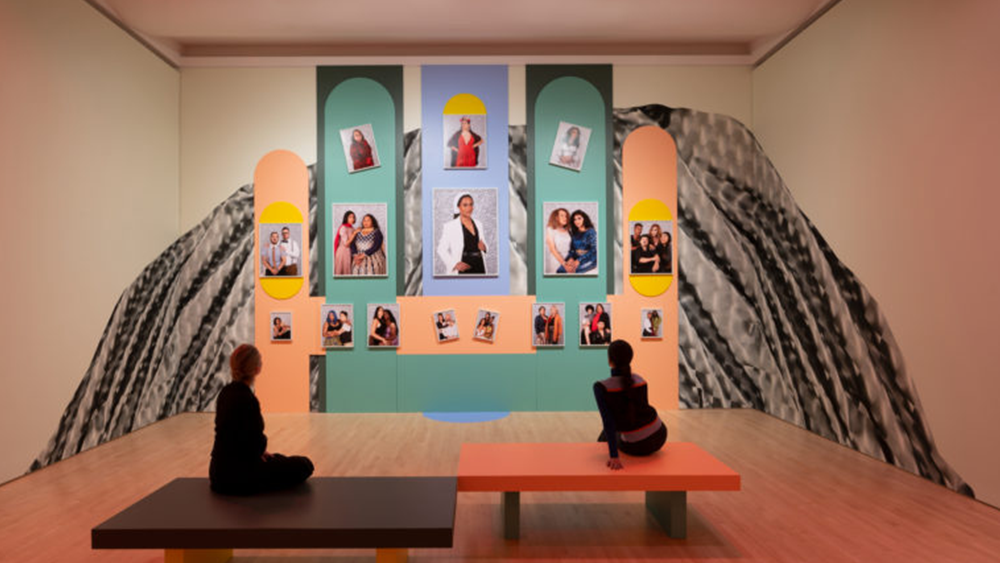 Two people sitting on benches inside of an SFMOMA gallery staring up at an artwork installation by artist Marcel Pardo Ariza.